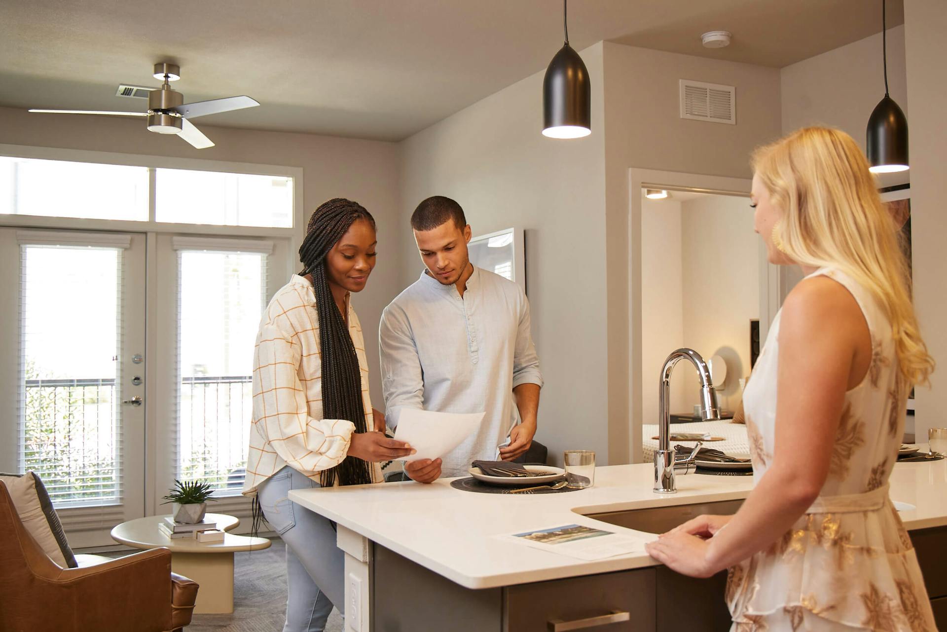 Three people standing at a kitchen island in an apartment